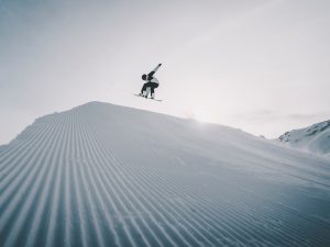 person jumping on snow covered ground during daytime